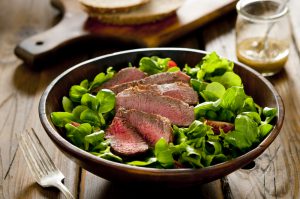 Plate of steak on top of salad  